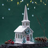 Decorative miniature church with a steeple, surrounded by Christmas elements on a dark green background. Decorative miniature church with a steeple, surrounded by Christmas elements on a dark green background.