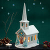 Decorative ceramic church with a lit candle on a dark background